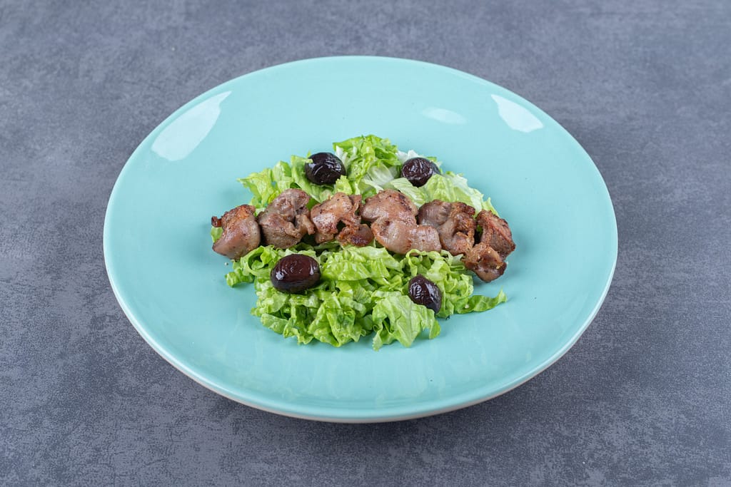 Lever op blauw bord, salade en olijven