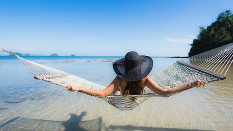 Vrouw geniet van de zon op het strand in een hangmat Vitamine-D